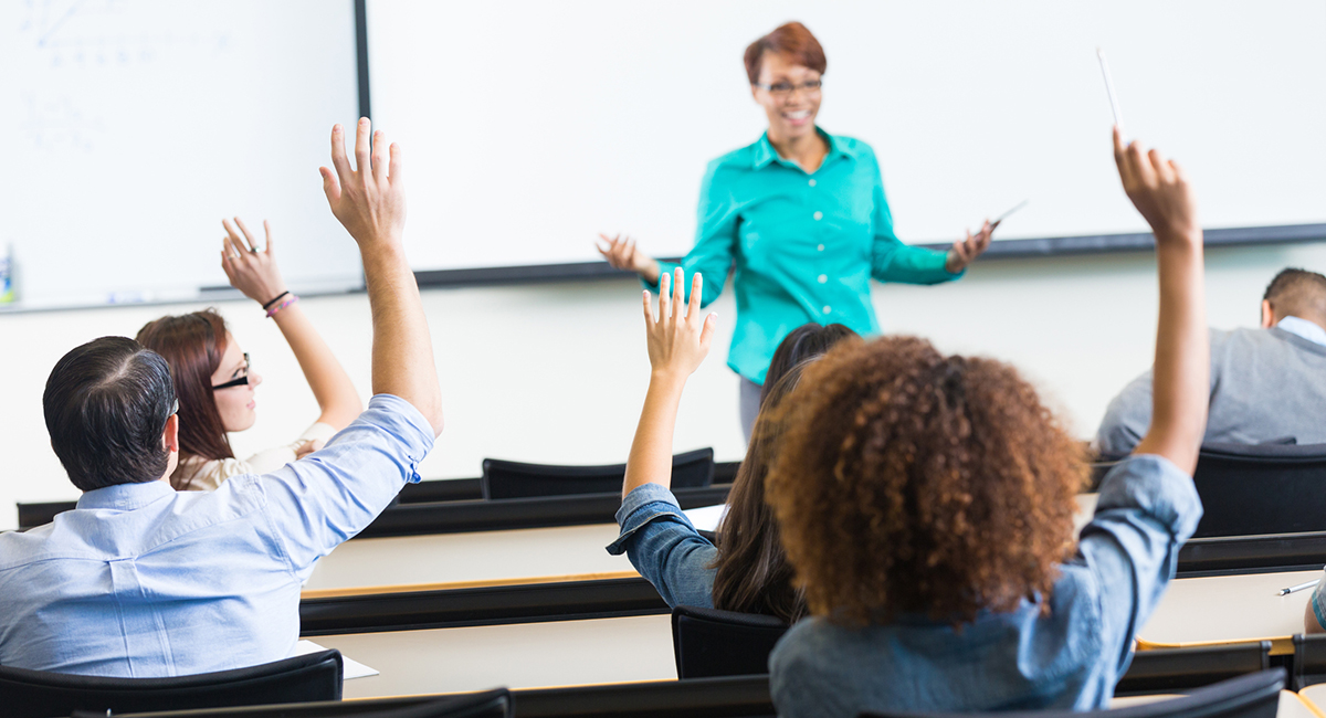 Students raising hands to ask question in lecture hall classroom