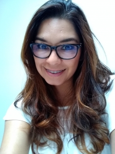 A woman with dark hair, glasses, and braces smiles for a selfie.