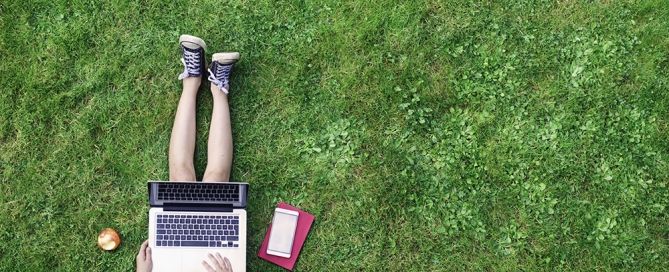 Female college student using laptop in grass