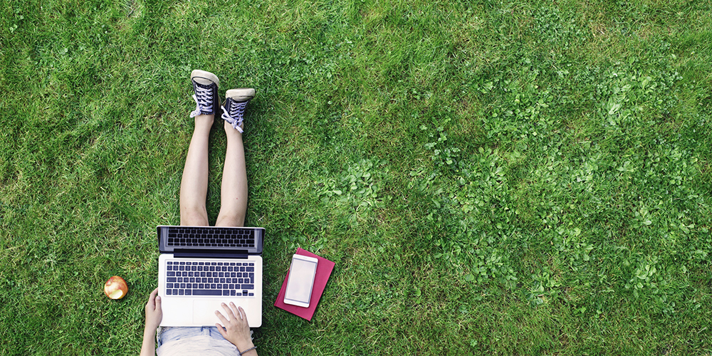 Female college student using laptop in grass