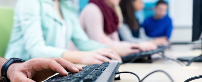 Anonymous students type in a computer lab