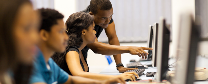 An instructor helps a student in a computer lab