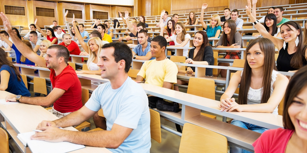 College students raising their hands in a lecture hall