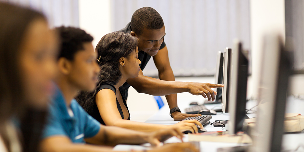 An instructor helps a student in a computer lab