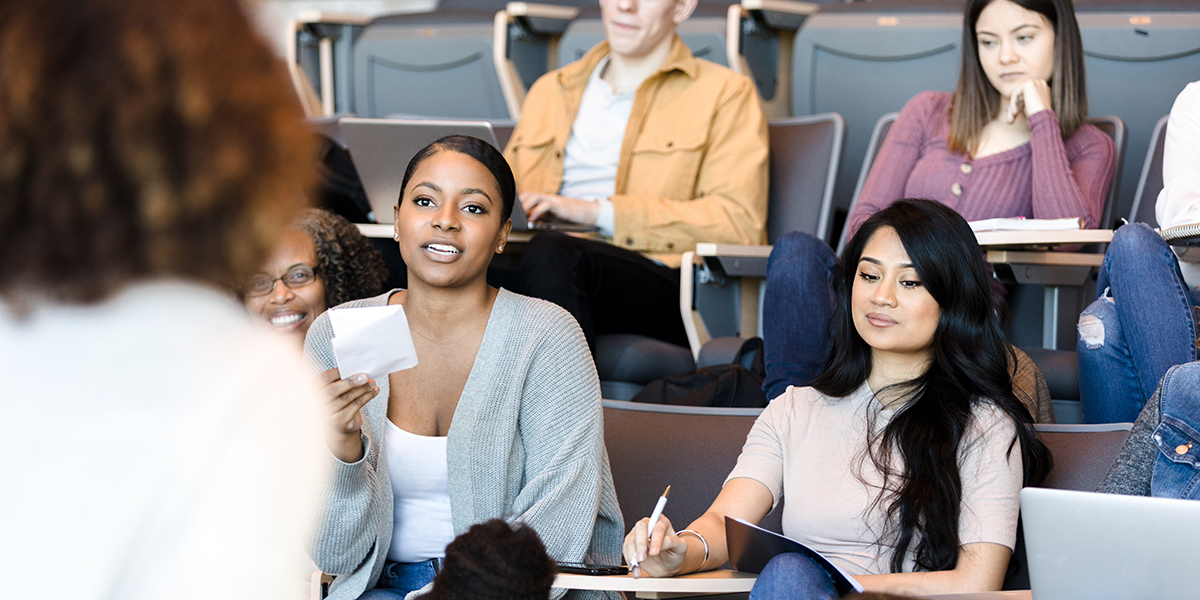 As an unrecognizable female college professor gives a lecture, a mid adult female student asks a question.