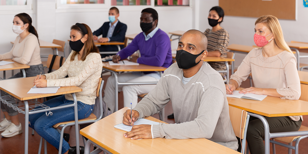 Students in mask sit at desks