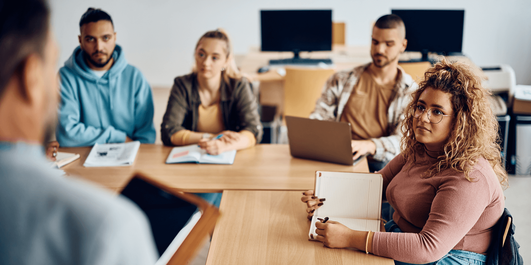 Four students sitting around a table listening to their instructor.