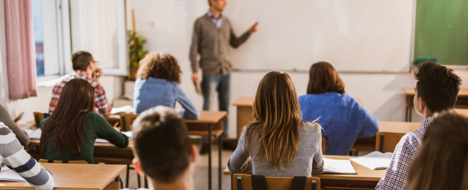 Back view of large group of high school students on a class in the classroom.