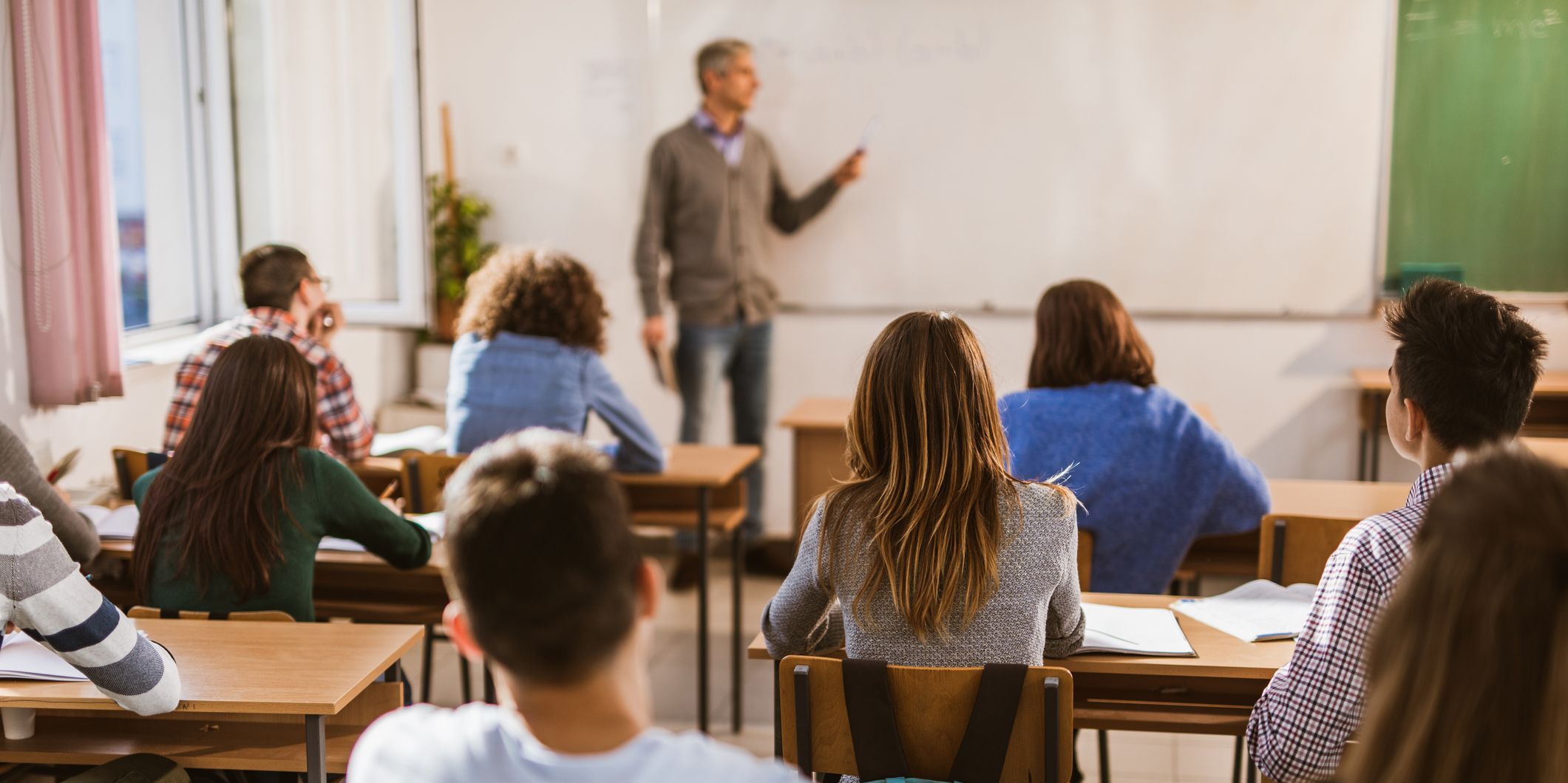 Back view of large group of high school students on a class in the classroom.